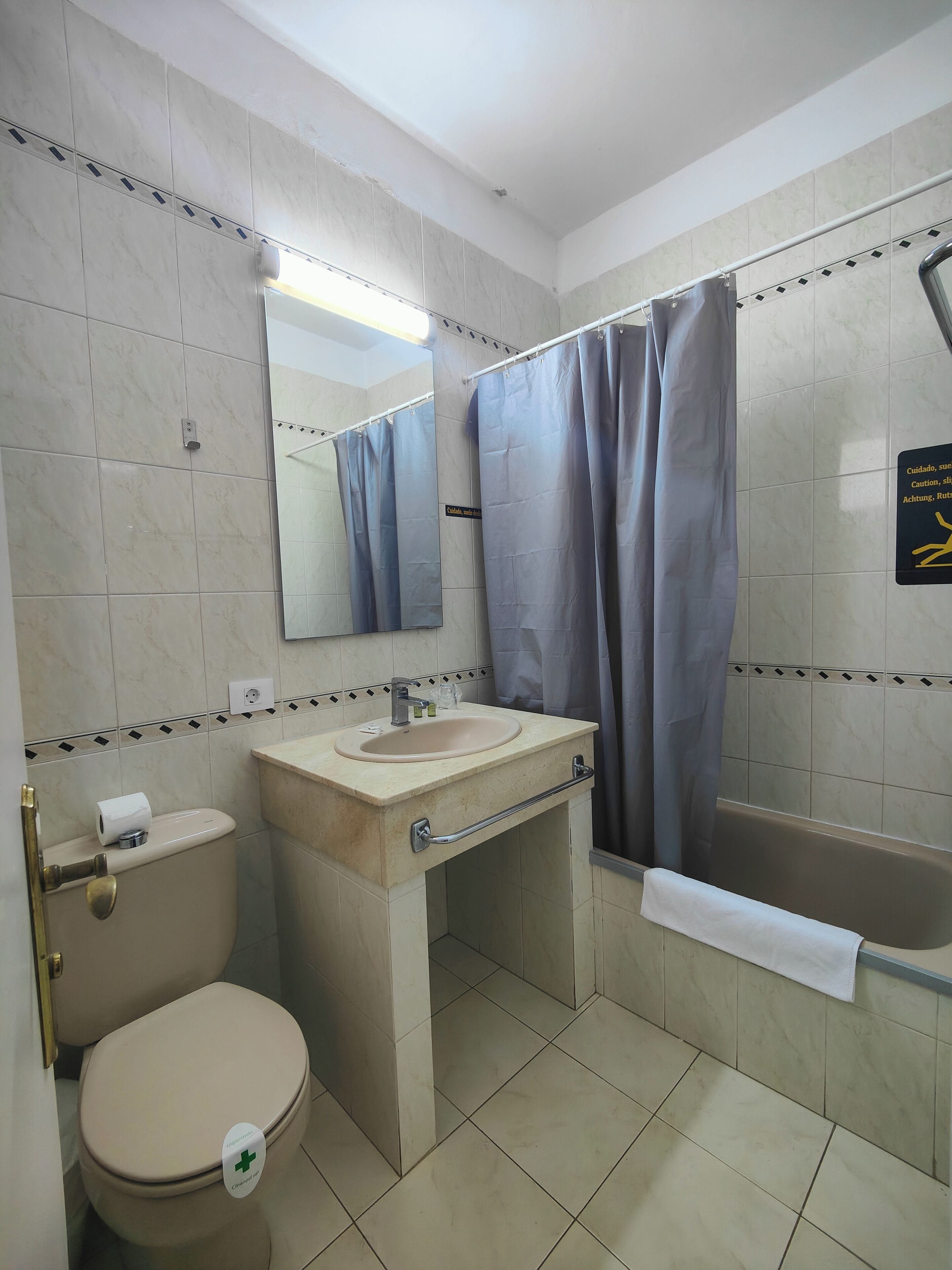 A bathroom with a toilet, sink, mirror, and bathtub.