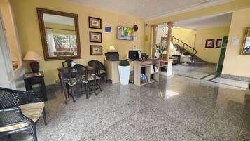 A lobby with a reception desk, chairs, a coffee table, and a staircase.