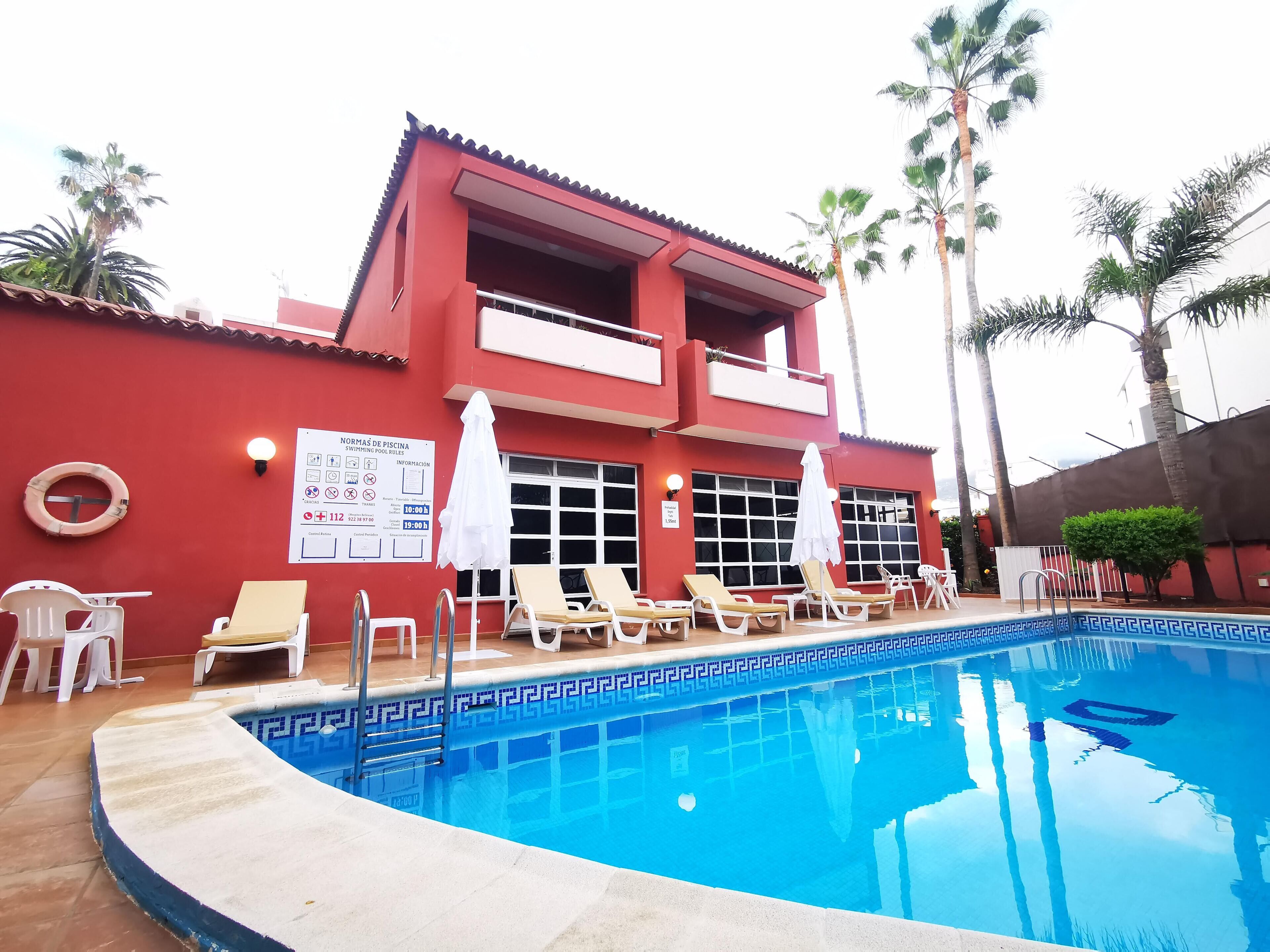Zona de piscina con sillones de descanso y un flotador en la pared.