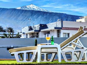 A terrace with a mountain view, a glass of wine, and a green bottle. - Hotel Don Candido (Puerto de la Cruz)