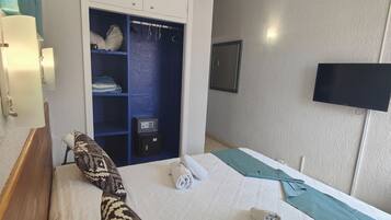 Una habitación de hotel con cama, armario, televisor de pantalla plana y ventilador de techo.