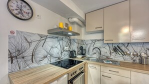Een moderne keuken met een zwart fornuis, witte kastjes en een decoratieve wand met boomtakken.