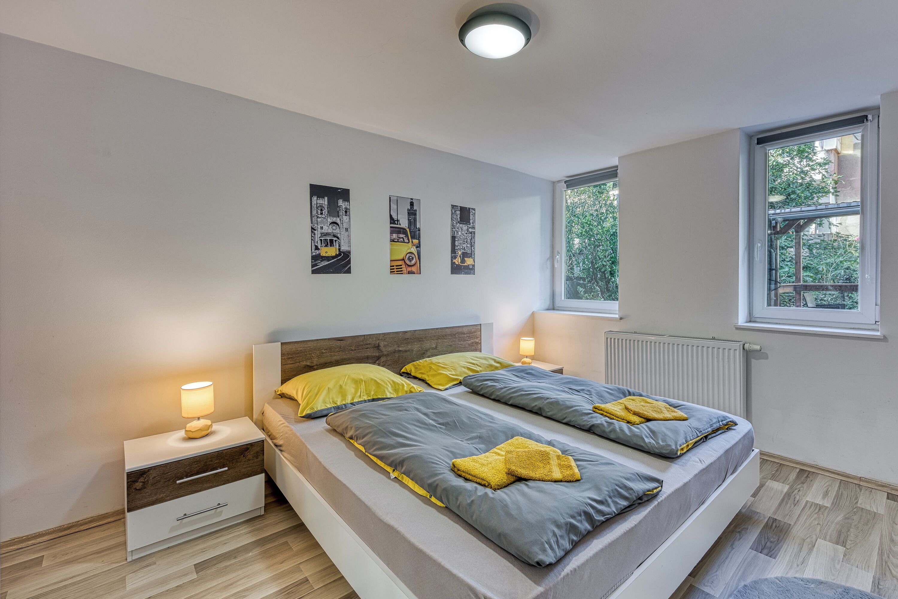 A modern bedroom with a bed, bedside tables, and a window.