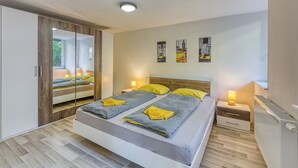Een moderne slaapkamer met een groot bed, nachtkastjes, een kledingkast en kunst aan de muur.