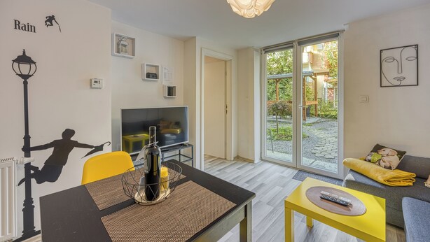 Een moderne woonkamer met een televisie, bank en eethoek.