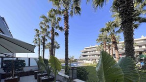 A rooftop terrace with potted plants, a pool, and a view of a building.