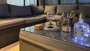 A glass-top table with a cocktail glass, a bottle, and a bottle of water.