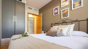 A bedroom with a bed, a wardrobe, and a shower area.