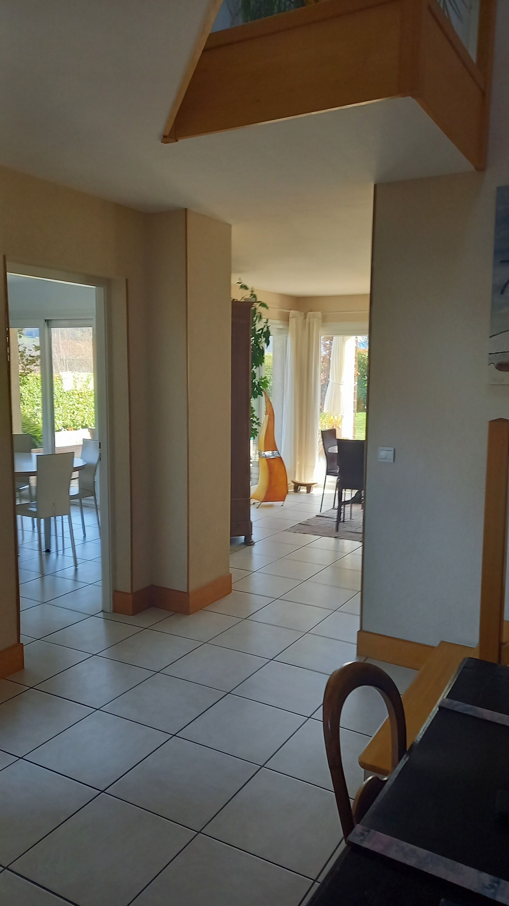 Une pièce spacieuse dotée d’un sol carrelé, d’un coin repas avec des chaises et une table, et offrant une vue sur l’extérieur par une fenêtre.