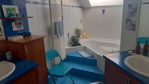 Un baño pequeño y funcional con tragaluz, bañera y lavamanos.