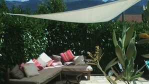 Terraza con sofá, cojines, piscina y vistas a la montaña.