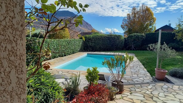 Una piscina rodeada de baldosas de piedra, con vistas a montañas y un cielo despejado.