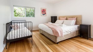 A bedroom with a bed, a crib, a window, and a cabinet.