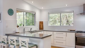A modern kitchen with a central island, white cabinetry, and a stainless steel stove.