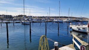 A marina with multiple boats docked, wooden pilings, and a lifebuoy. - Large holiday house with great seaview - sauna and hottub (Glesborg, Bønnerup Strand)