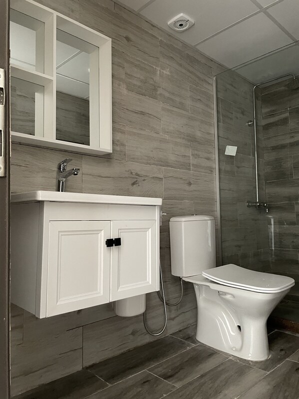 Une salle de bain moderne avec un meuble-lavabo blanc, une cabine de douche en verre et des toilettes.