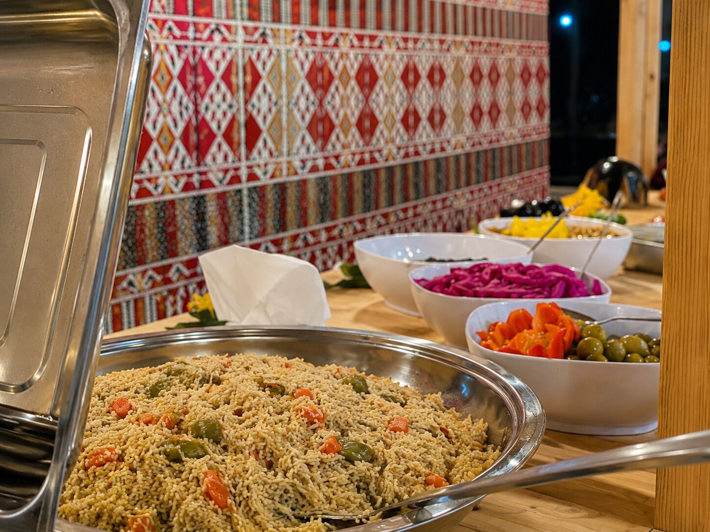 A buffet table with various dishes including rice, vegetables, and salads.