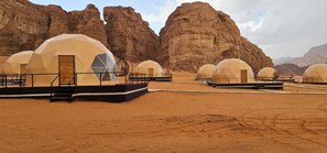 Un paysage désertique où de nombreuses tentes en forme de dôme sont disposées en rangées.