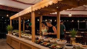 A buffet setup with multiple food stations and a wooden counter. - Hasan Zawaideh Luxury Camp 2 (Wadi Rum)