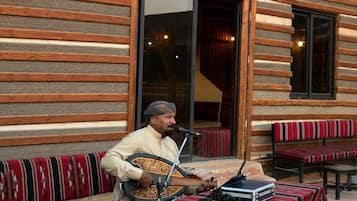 A person playing a stringed instrument outdoors, with a microphone and electronic equipment on a table.