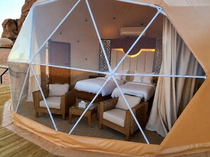 Un alojamiento con carpa, una cama, dos sillas, una mesa y una lámpara de mesa pequeña.