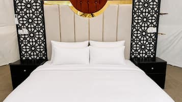 A bed with a tufted headboard, two bedside tables, and decorative panels on either side.