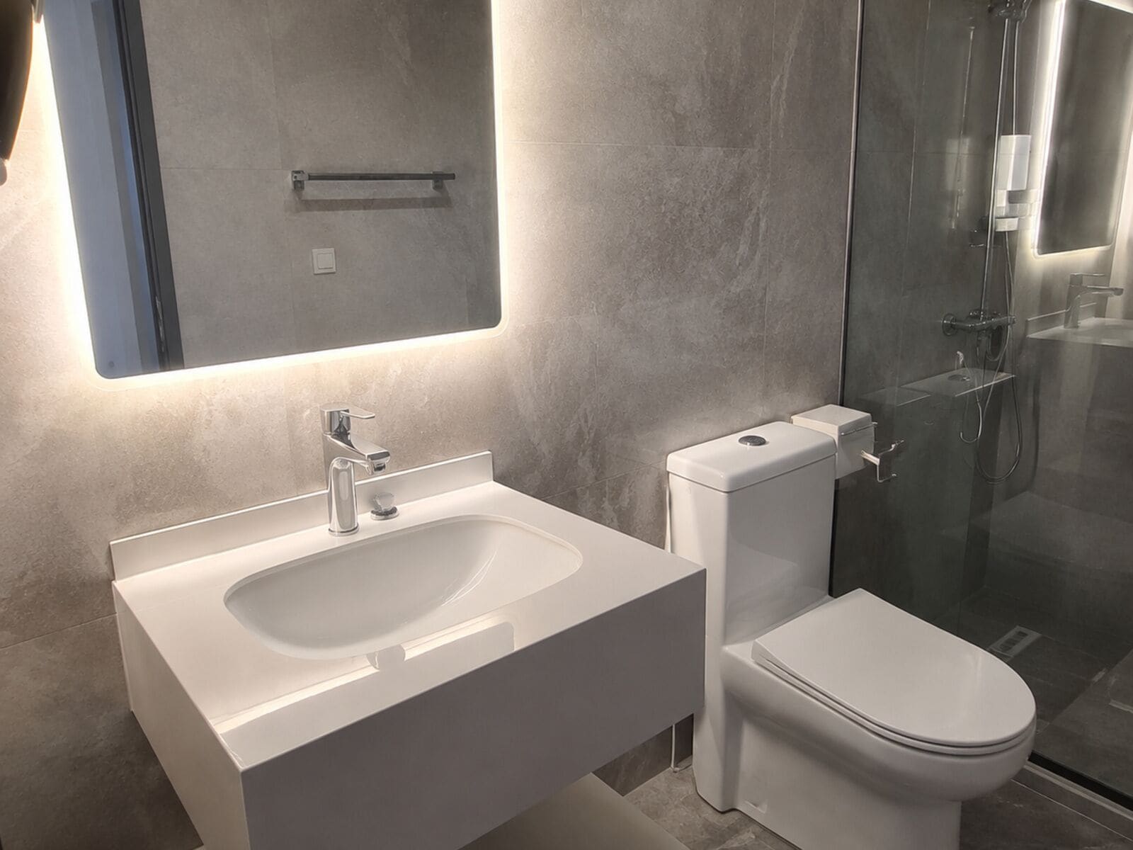 A modern bathroom with a white sink, a toilet, and a glass shower enclosure.