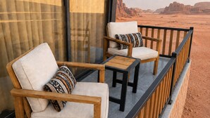A balcony with two wooden chairs and a small table, overlooking a desert landscape. - Hasan Zawaideh Luxury Camp 2 (Wadi Rum)
