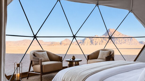 A tented room with a bed, two chairs, a small table, and a candle. - Hasan Zawaideh Luxury Camp 2 (Wadi Rum)