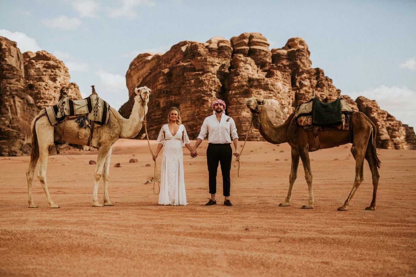 A desert landscape with two camels and a person in the center.