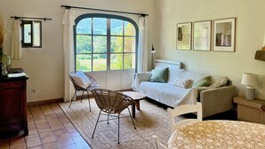 A room with a large window, a sofa, a chair, a table, and a lamp. - Lavender, Luberon view, pool, air-conditioning : Villa Mas des Lavandes 2 BR. 4* (Céreste)