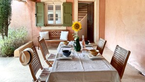 A dining area with a table set for four, wooden chairs, a bench, and a view of a staircase. - Lavender, Luberon view, swimming pool, AC : Villa Mas du Luberon 15 km from Apt (Céreste)