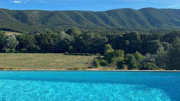 A clear blue pool with a view of green hills and trees in the background. - Lavender, Luberon view, swimming pool, AC : Villa Mas du Luberon 15 km from Apt (Céreste)