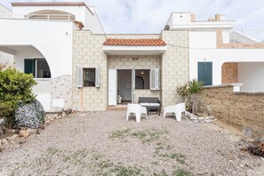 A modern house with a gravel driveway, white furniture, and a small patio area. - Villetta Marta (Ugento)