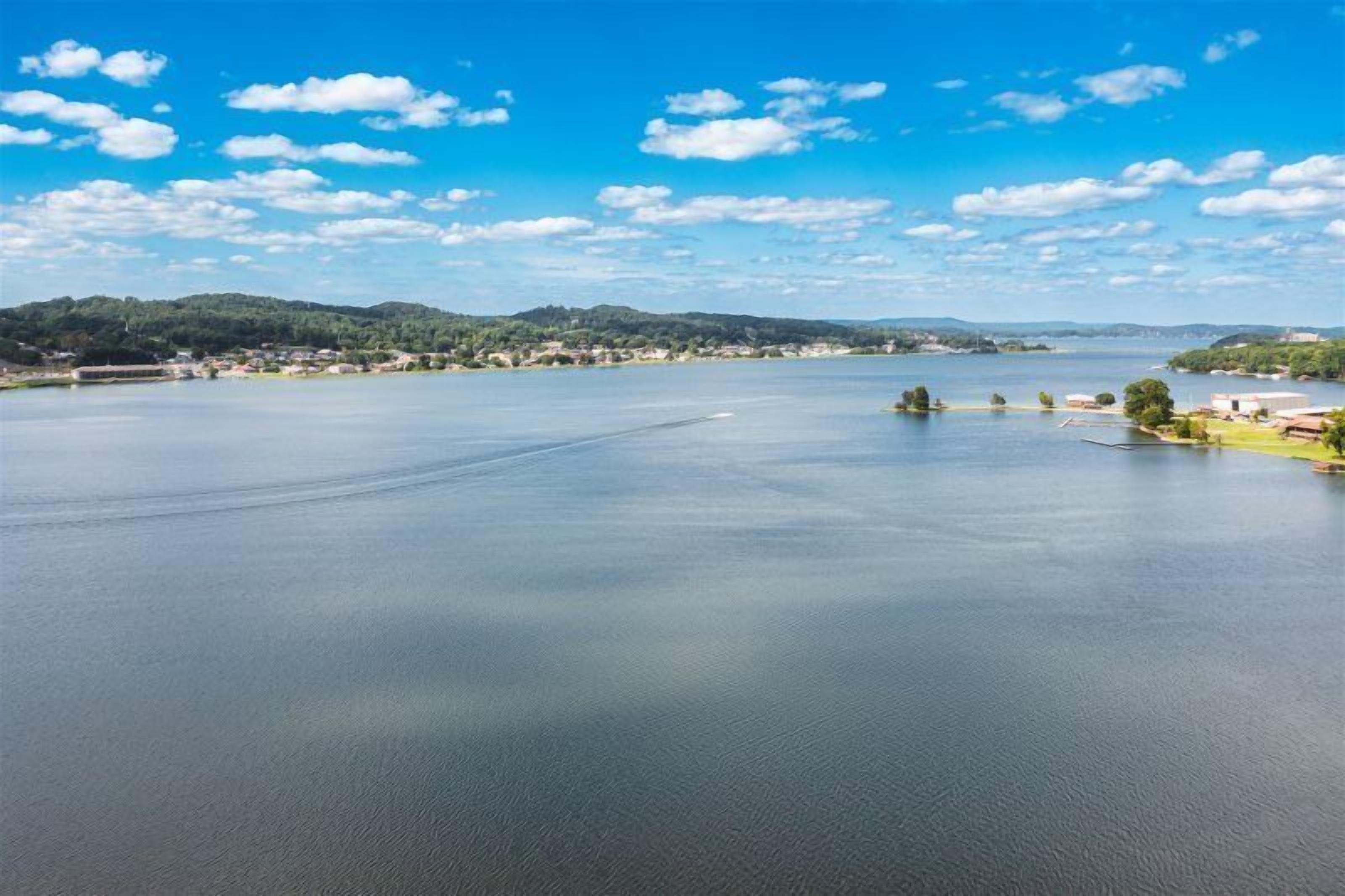 A large body of water with a distant shoreline, surrounded by hills and a clear sky.
