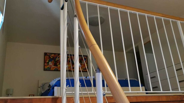 Una habitación con cama, ventana y barandilla.
