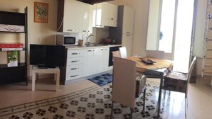Una cocina compacta con armarios blancos, un microondas y un comedor con mesa y sillas.