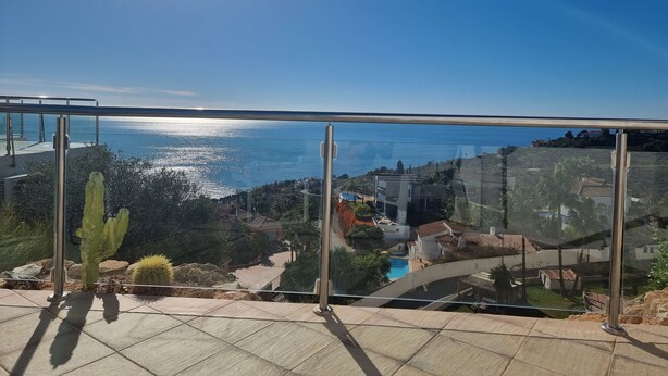 Un balcón con vistas despejadas al mar, una piscina y edificios circundantes.