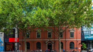A red brick building with a sign reading "Upper West Side" and a row of parked bicycles in front. - Homely 1BR Apt Near Southern Cross Station w/ Pool (Melbourne)