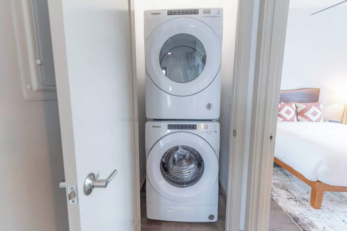 A compact, modern laundry room with two stacked front-loading washing machines.