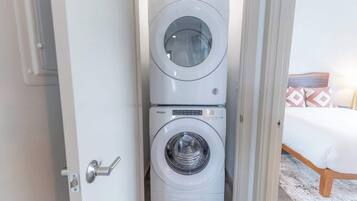 A compact, modern laundry room with two stacked front-loading washing machines.