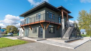 Une maison moderne à deux étages, dotée d’un balcon, d’un escalier et d’un garage.