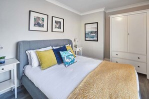 A bedroom with a bed, bedside tables, a wardrobe, and framed pictures on the wall.