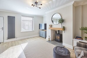 A living room with a fireplace, a television, and a large window.