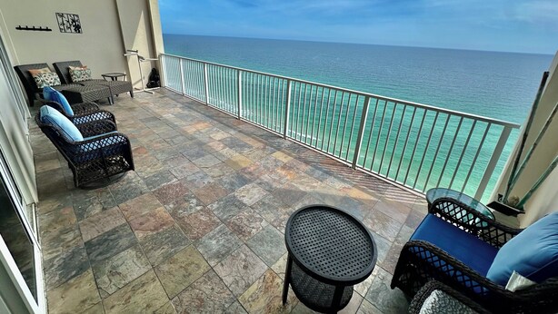 A balcony with wicker furniture, a round table, and a view of the ocean. - Asian Themed, Beach-Front, Penthouse Condo, Huge Balcony, Free Beach Chairs! (Panama City Beach)