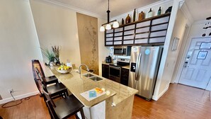 A kitchen with a central island, a microwave, a refrigerator, and a sink. - Asian Themed, Beach-Front, Penthouse Condo, Huge Balcony, Free Beach Chairs! (Panama City Beach)