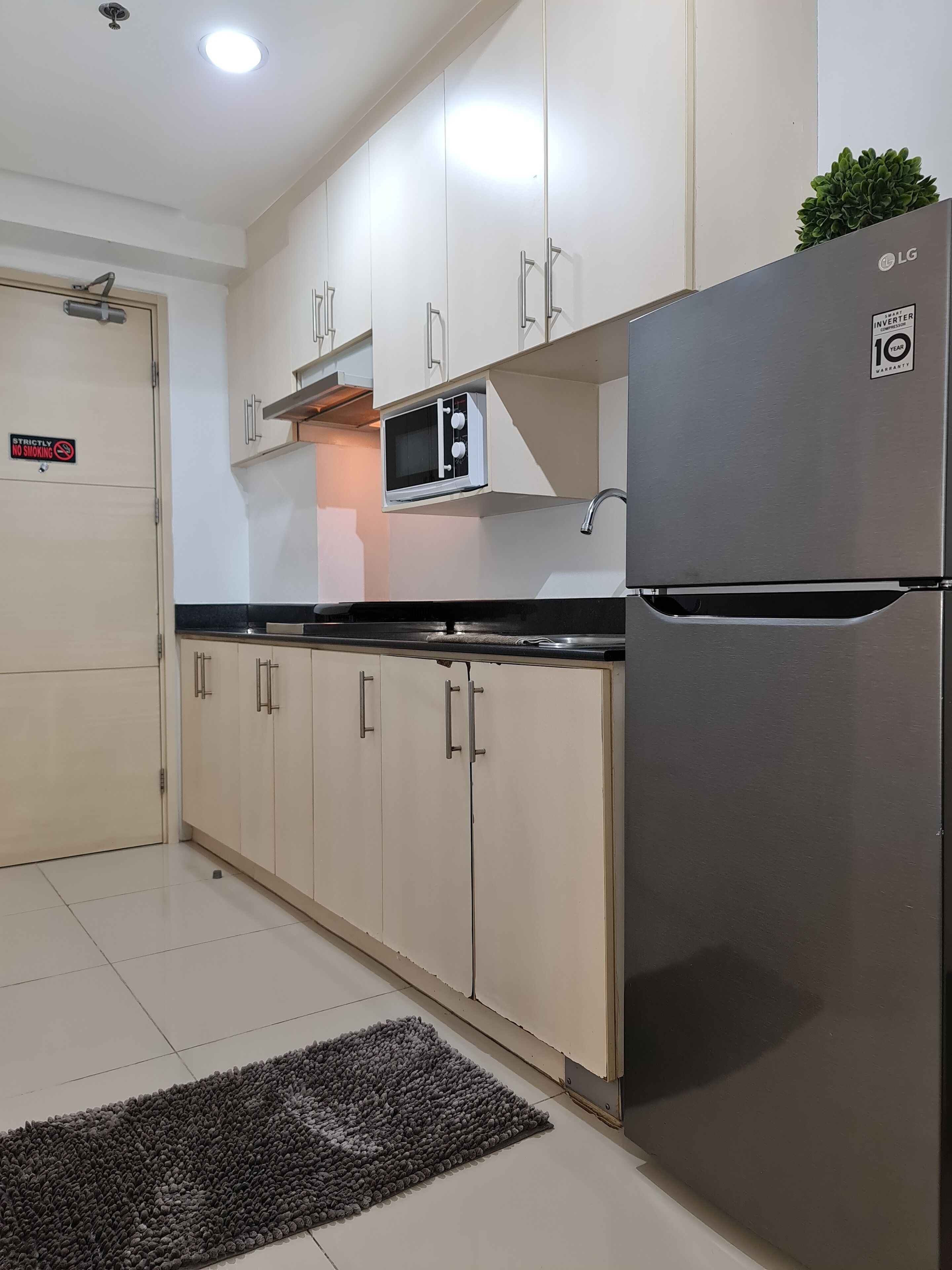 A modern kitchen with white cabinets, a built-in microwave, and a stainless steel refrigerator.