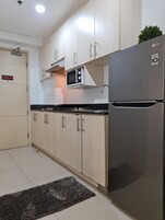 A modern kitchen with white cabinets, a built-in microwave, and a stainless steel refrigerator.