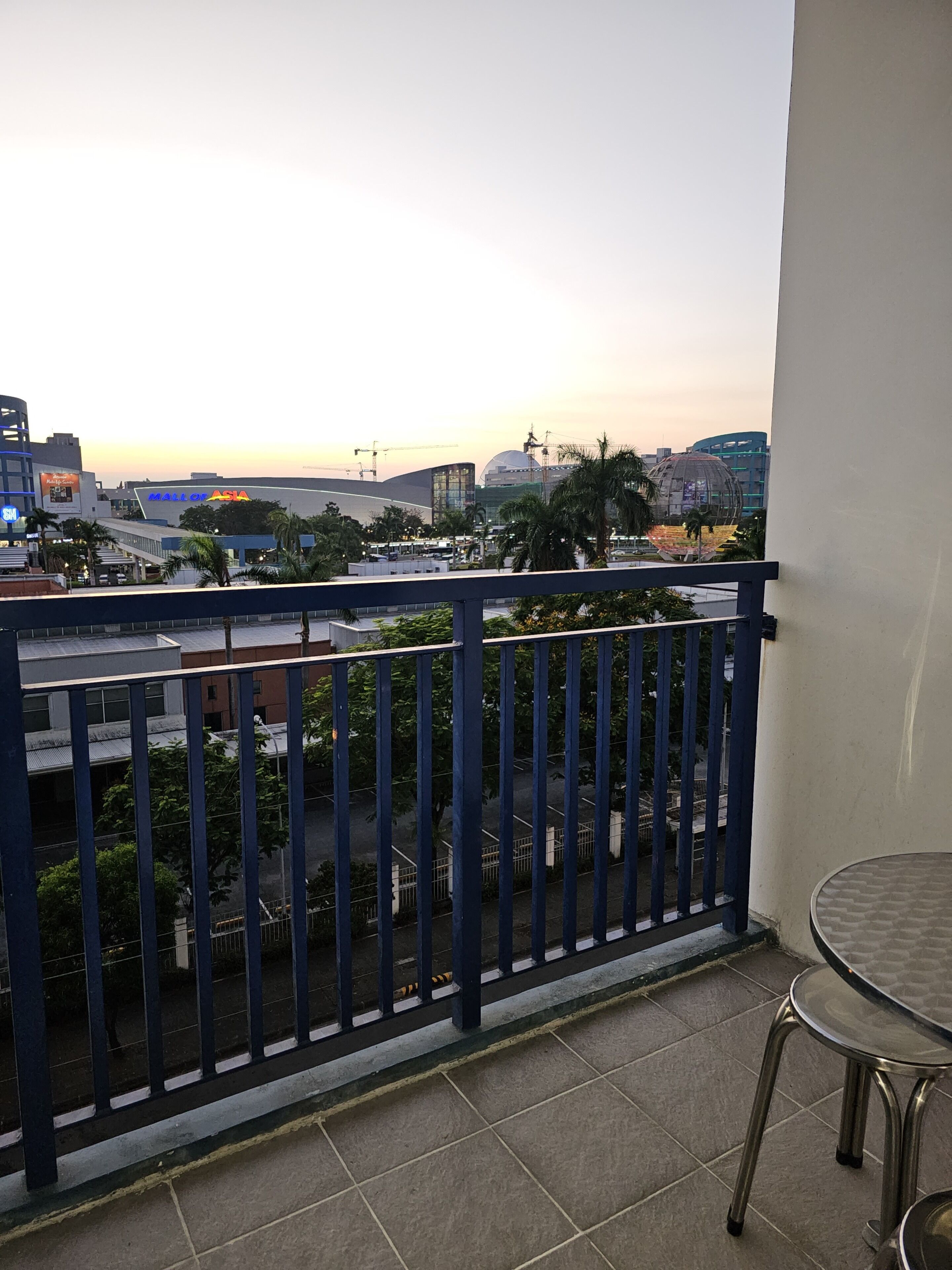 A balcony with a view of a cityscape, including a large stadium and modern buildings.