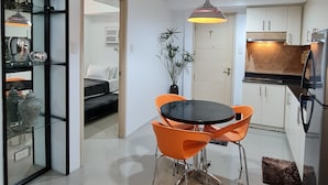 A modern kitchen with white cabinets, a black countertop, and a stainless steel refrigerator. - Sea Residences - Condo R Us (Pasay)